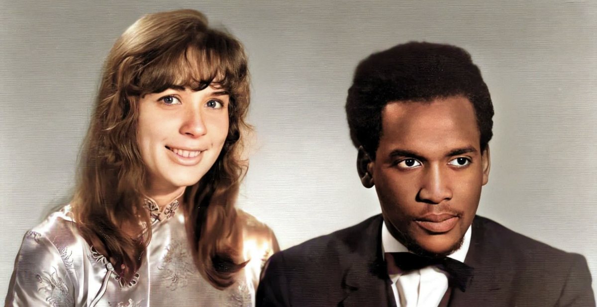 Maryanne Raphael and Lennox Raphael smiling in a hand-tinted 1960s portrait. She has long brown hair; he wears a suit and bow tie.