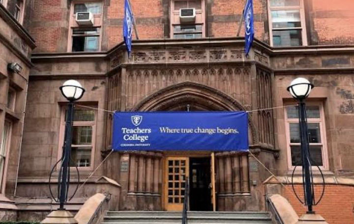 The Gothic stone entrance of Teachers College, with a blue banner over the doors that reads Teachers College, Columbia University: Where true change begins.